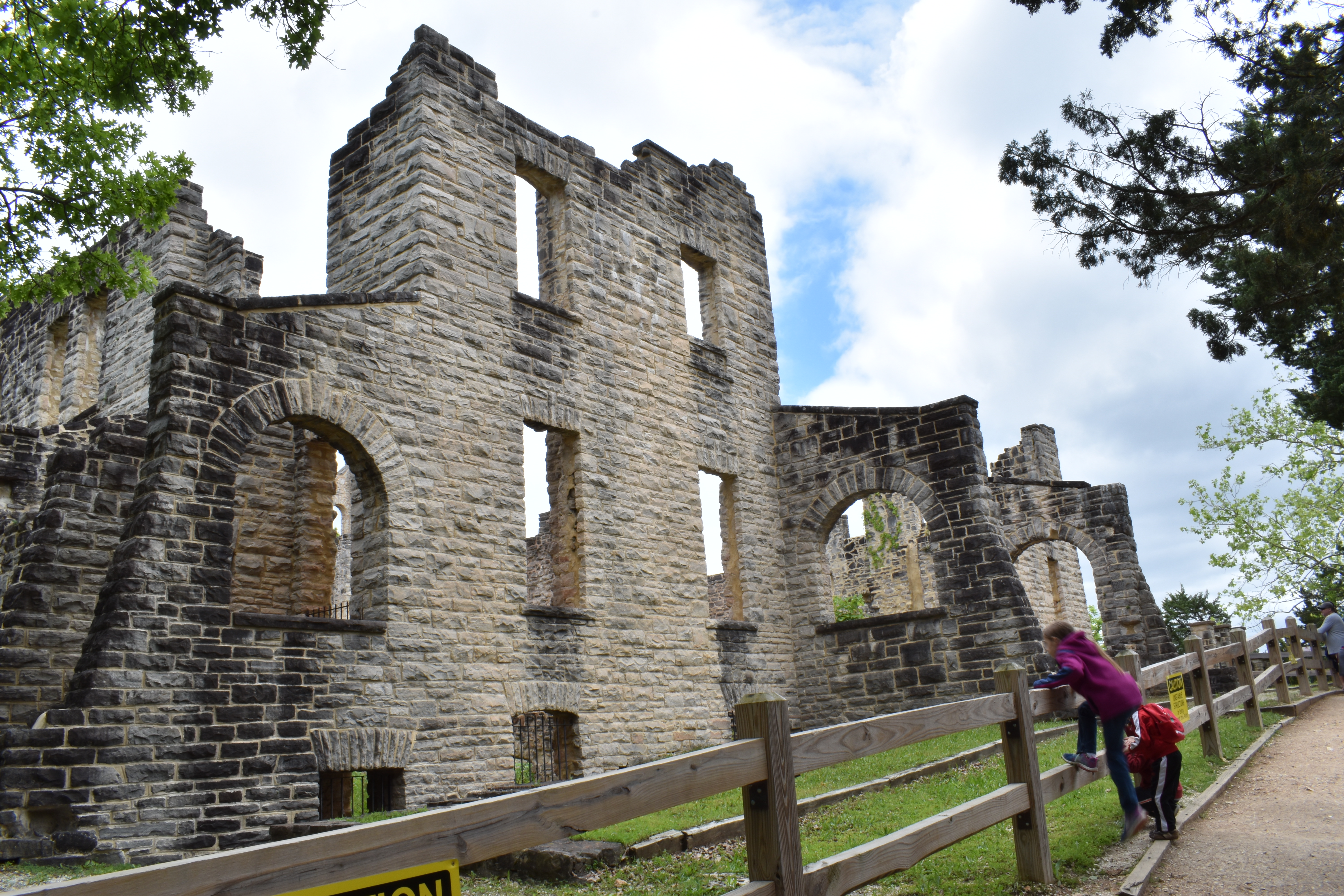 Kids leaning over a fence to see more of the ruins at Ha Ha Tonka